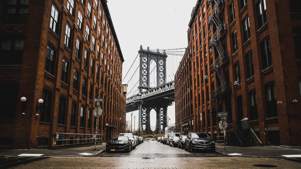 picture of brooklyn bridge with two apartment blocks beside the street