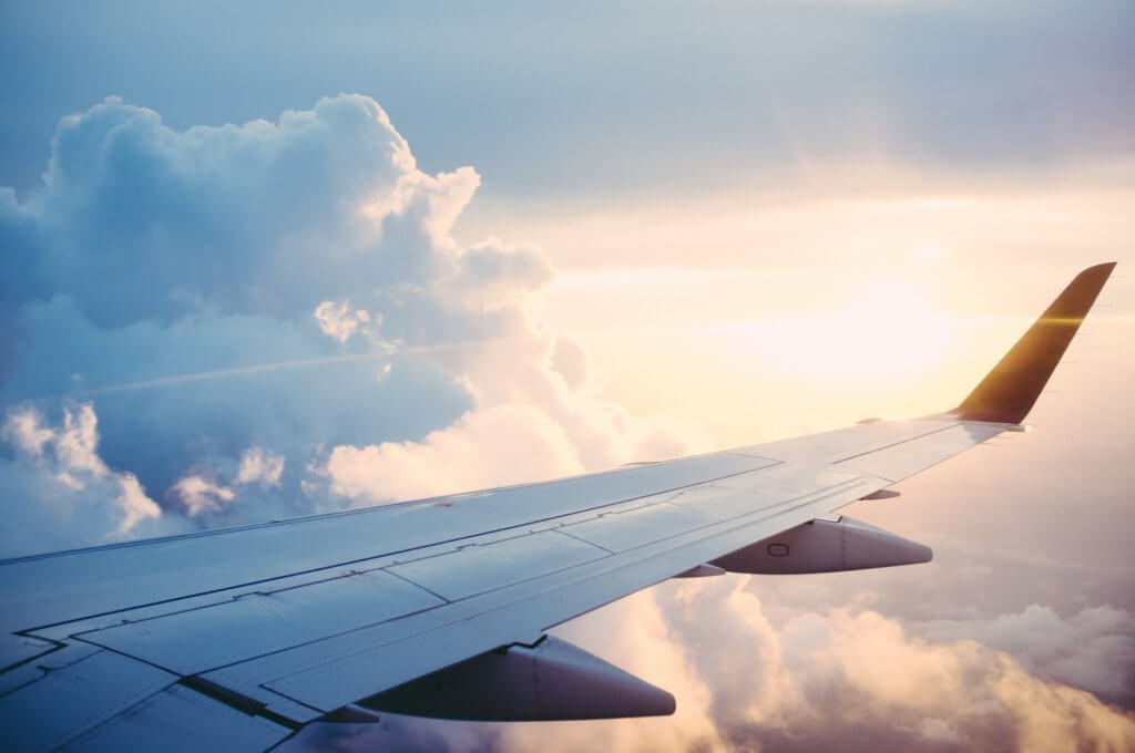 Airplane wing with clouds and sunny sky