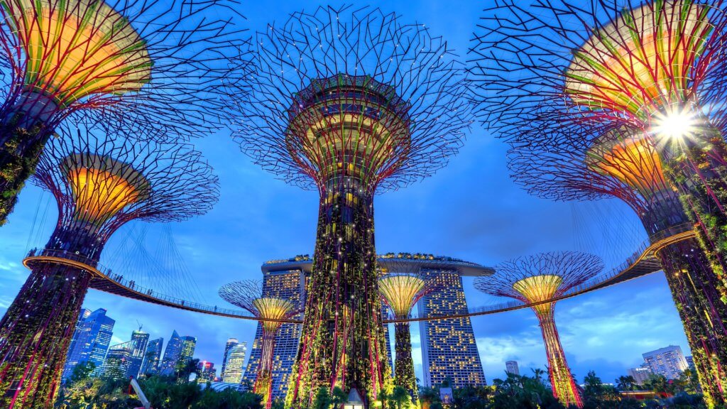 The Gardens by The Bay in Singapore, one of Asia's top bleisure destinations, lit up at night with Marina Bay Sands and the Singapore City skyline in the background 